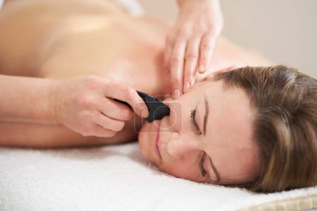 Téléchargez les photos : Femme ayant un massage gua sha dans le salon. Photo de haute qualité - en image libre de droit