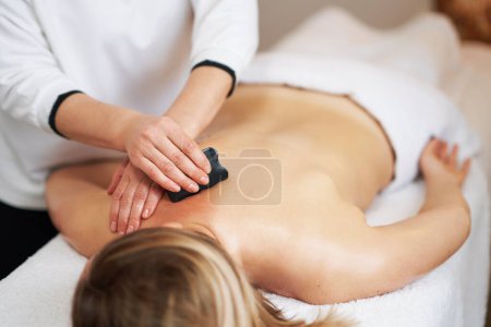 Woman having a gua sha massage in salon. High quality photo