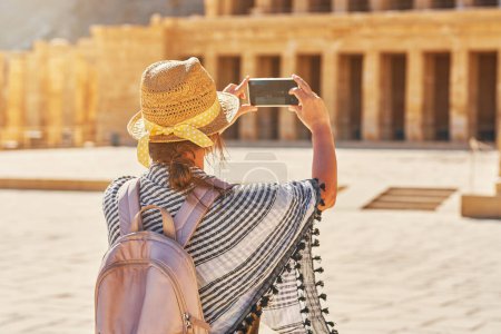 Téléchargez les photos : Femme touristique prenant des photos od ruines Temple mortuaire de Hatchepsout. Photo de haute qualité - en image libre de droit