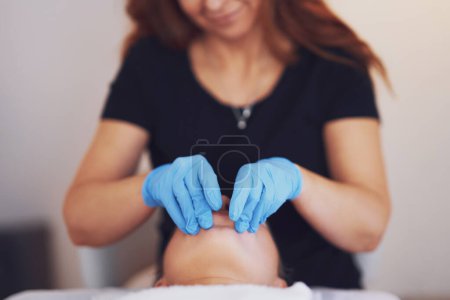 Frau mit Mundmassage in blauen Handschuhen. Hochwertiges Foto