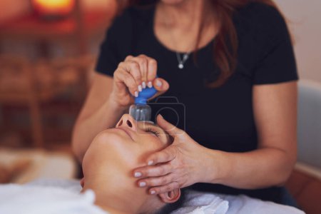 Téléchargez les photos : Femme ayant un massage de tasse de visage dans le salon. Photo de haute qualité - en image libre de droit