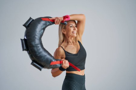 Téléchargez les photos : Photo d'une jolie femme blonde faisant de l'entraînement avec un sac de sable. Photo de haute qualité - en image libre de droit