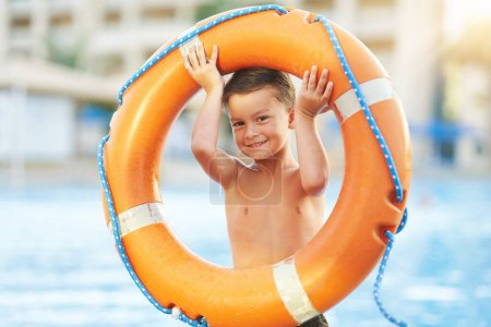 Téléchargez les photos : Photo d'un jeune garçon tenant une bouée de sauvetage à la piscine. Photo de haute qualité - en image libre de droit