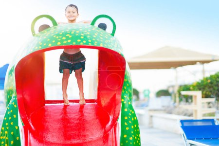 Téléchargez les photos : Photo de jeune garçon jouant dans un parc aquatique extérieur. Photo de haute qualité - en image libre de droit