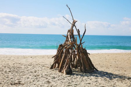 Téléchargez les photos : Cabane de plage. Une petite structure construite à partir de branches de bois flotté sur la plage. A l'abri de la tempête. Drift Maison en bois - en image libre de droit