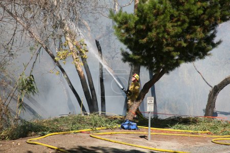 Foto de Lake Forest, CA - USA -November 6, 2022: Arson Fire set in the brush of a Bike Path in Orange County California. Fire, and Police responded to quickly extinguish the flames and protect properties - Imagen libre de derechos