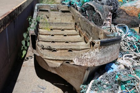 Photo for Broken Boat. An old broken boat thrown into a garbage pile on the side of a dock. Old Broken Boats are of no use to fishermen or people. - Royalty Free Image