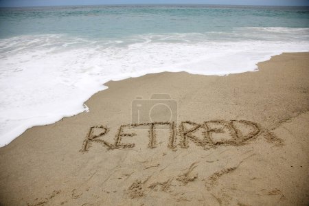 Téléchargez les photos : Retired written in the sand on the beach.  message handwritten on a smooth sand beach - en image libre de droit