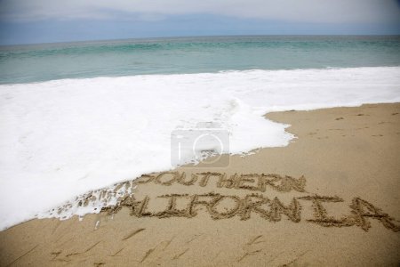 Téléchargez les photos : Southern California written in the sand on the beach.  message handwritten on a smooth sand beach - en image libre de droit