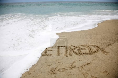 Téléchargez les photos : Retired  written in the sand on the beach.  message handwritten on a smooth sand beach - en image libre de droit