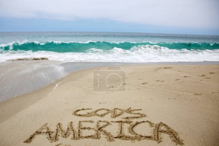 Foto de God's america written in the sand on the beach.  message handwritten on a smooth sand beach - Imagen libre de derechos