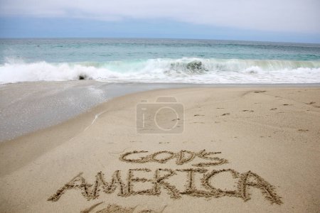Téléchargez les photos : Le sourire américain de Dieu écrit dans le sable sur la plage. message manuscrit sur une plage de sable lisse - en image libre de droit