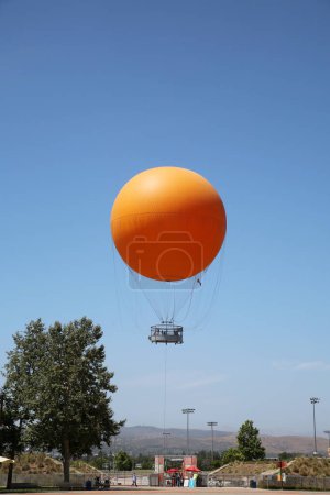Foto de Irvine, California - USA - June 2, 2022: The Orange Balloon in the Great Park in Irvine, California. A beautiful free ride in the Orange Balloon reaching up 400 feet into the sky. - Imagen libre de derechos