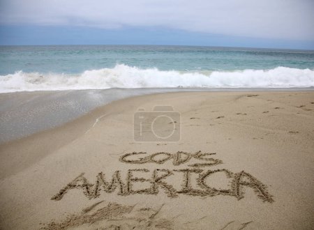 Téléchargez les photos : Le sourire américain de Dieu écrit dans le sable sur la plage. message manuscrit sur une plage de sable lisse - en image libre de droit
