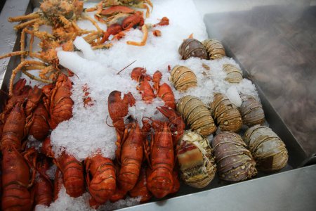 Téléchargez les photos : Du homard. Queues de homard sur la glace. Queues de homard cuites et crues à vendre sur un marché de fruits de mer. - en image libre de droit