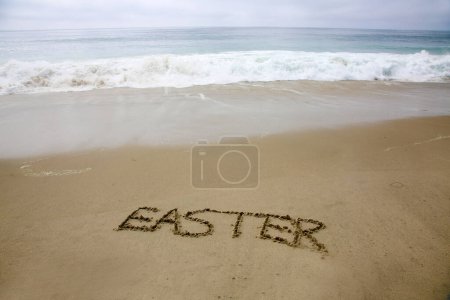 Téléchargez les photos : Easter. The word EASTER written in the sand by the ocean. - en image libre de droit