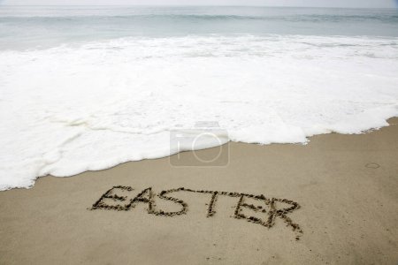 Foto de Easter. The word EASTER written in the sand by the ocean. - Imagen libre de derechos