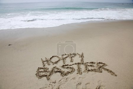 Téléchargez les photos : Hoppy Easter. The words HOPPY EASTER written in the sand by the ocean. - en image libre de droit