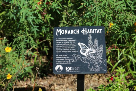 Foto de Costa Mesa, California - Estados Unidos - 3 de octubre de 2022: Hábitat del monarca. Señal de advertencia en un jardín con plantas de Milkweed para mariposas e insectos polinizadores advirtiendo sobre la intoxicación por Milkweed. - Imagen libre de derechos