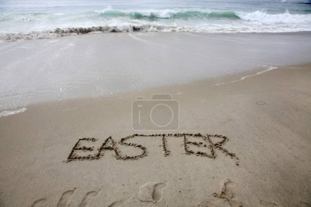 Téléchargez les photos : Easter written in the sand on the beach.  message handwritten on a smooth sand beach - en image libre de droit