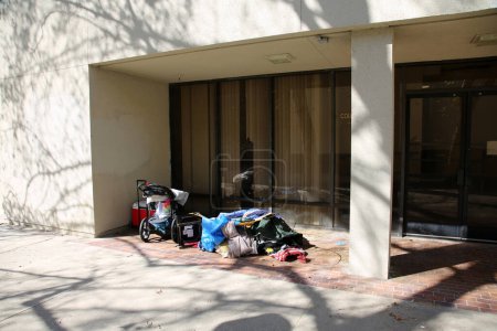 Photo for Santa Ana, California - USA -3-12-2022: Outdoor shelter of homeless person next to a office window. Homelessness is a tragic experience world wide. Homeless bedding and possessions. - Royalty Free Image