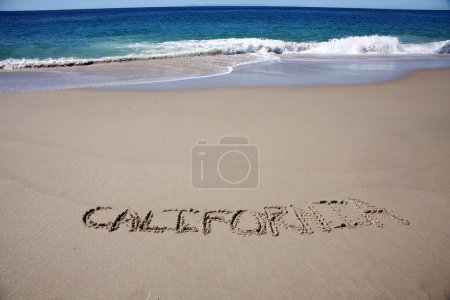 Téléchargez les photos : California written in the sand on the beach.  message handwritten on a smooth sand beach - en image libre de droit