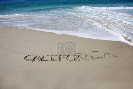 Téléchargez les photos : California written in the sand on the beach.  message handwritten on a smooth sand beach - en image libre de droit