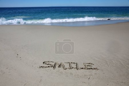 Téléchargez les photos : Smile written in the sand on the beach.  message handwritten on a smooth sand beach - en image libre de droit