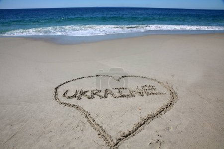 Téléchargez les photos : Ukraine written in the sand on the beach.  message handwritten on a smooth sand beach - en image libre de droit