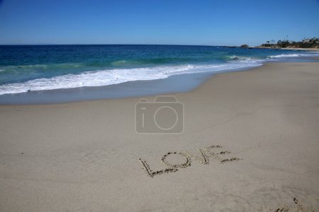 Téléchargez les photos : Love  written in the sand on the beach.  message handwritten on a smooth sand beach - en image libre de droit