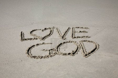 Téléchargez les photos : Love god  written in the sand on the beach.  message handwritten on a smooth sand beach - en image libre de droit