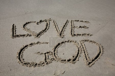 Téléchargez les photos : Love god written in the sand on the beach.  message handwritten on a smooth sand beach - en image libre de droit