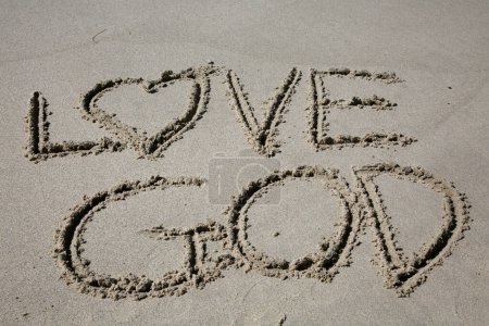 Téléchargez les photos : Love god written in the sand on the beach.  message handwritten on a smooth sand beach - en image libre de droit