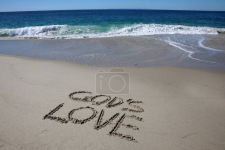 Foto de God's love written in the sand on the beach.  message handwritten on a smooth sand beach - Imagen libre de derechos