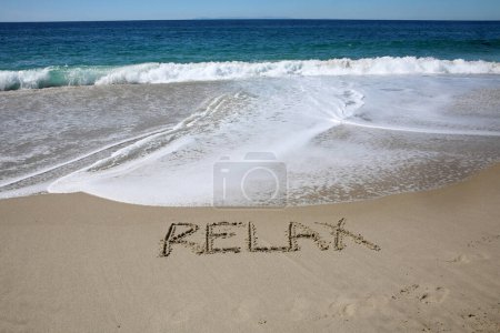 Téléchargez les photos : Relax written in the sand on the beach.  message handwritten on a smooth sand beach - en image libre de droit
