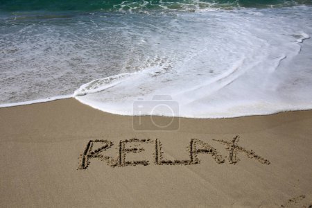 Téléchargez les photos : Relax  written in the sand on the beach.  message handwritten on a smooth sand beach - en image libre de droit