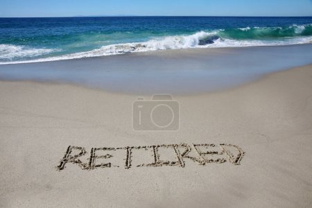 Foto de Retired written in the sand on the beach.  message handwritten on a smooth sand beach - Imagen libre de derechos
