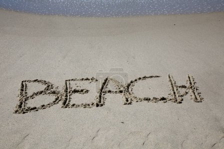 Foto de Beach written in the sand on the beach.  message handwritten on a smooth sand beach - Imagen libre de derechos