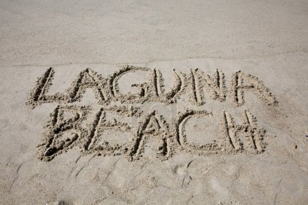 Foto de Laguna beach written in the sand on the beach.  message handwritten on a smooth sand beach - Imagen libre de derechos
