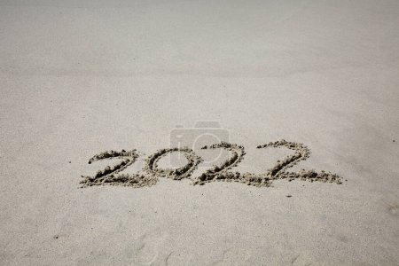 Téléchargez les photos : 2022 written in the sand on the beach.  message handwritten on a smooth sand beach - en image libre de droit