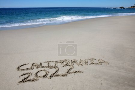Foto de California written in the sand on the beach.  message handwritten on a smooth sand beach - Imagen libre de derechos