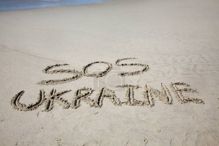 Téléchargez les photos : Sos ukraine written in the sand on the beach.  message handwritten on a smooth sand beach - en image libre de droit