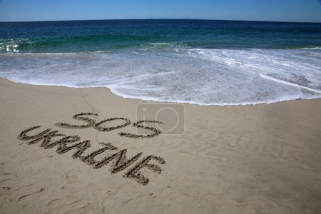 Téléchargez les photos : Sos  ukraine in the sand on the beach.  message handwritten on a smooth sand beach - en image libre de droit