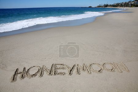 Téléchargez les photos : Hoheymoon written in the sand on the beach.  message handwritten on a smooth sand beach - en image libre de droit