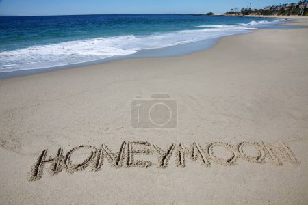 Téléchargez les photos : Honeymoon written in the sand on the beach.  message handwritten on a smooth sand beach - en image libre de droit