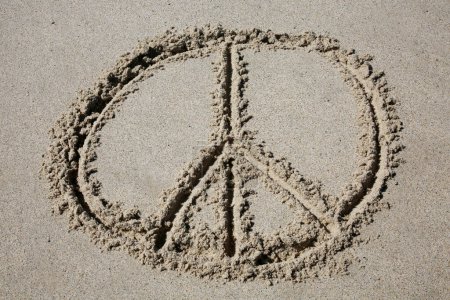 Téléchargez les photos : Peace sign written in the sand on the beach.  message handwritten on a smooth sand beach - en image libre de droit