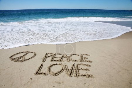 Téléchargez les photos : Peace  love written in the sand on the beach.  message handwritten on a smooth sand beach - en image libre de droit