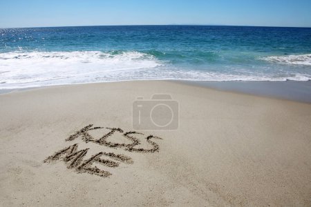Téléchargez les photos : Kiss me written in the sand on the beach.  message handwritten on a smooth sand beach - en image libre de droit