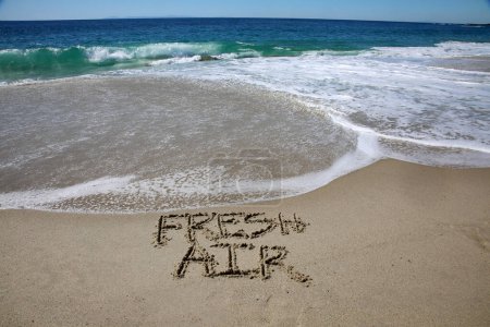 Foto de Fresh air written in the sand on the beach.  message handwritten on a smooth sand beach - Imagen libre de derechos