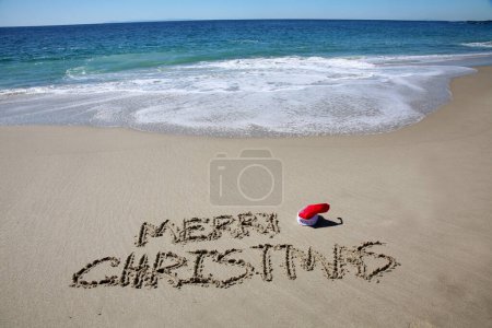 Téléchargez les photos : Merry christmas written in the sand on the beach.  message handwritten on a smooth sand beach - en image libre de droit